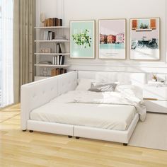 a white bed sitting on top of a hard wood floor next to a book shelf