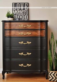 an old dresser is painted black with gold hardware and has a potted plant on top