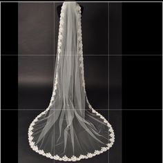 the back of a wedding veil with white flowers and laces on it, against a black background