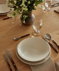 the table is set with silverware and flowers in a vase on top of it