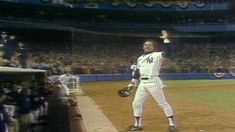 a baseball player standing on top of a field in front of a crowd at a game