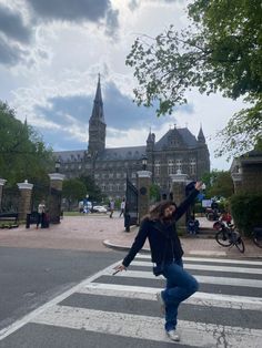 a woman standing in the middle of a crosswalk with her arms up and legs spread wide