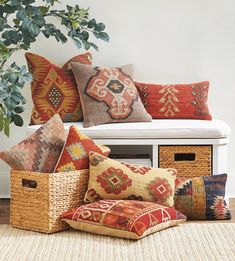 a bunch of pillows sitting on top of a white bench next to a potted plant