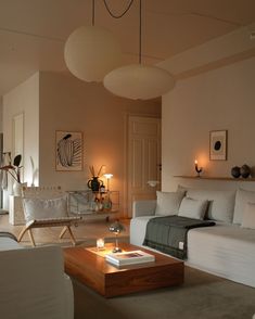 a living room filled with white furniture and lamps on top of it's tables