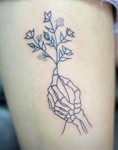 a woman's leg with a tattoo on it that has a plant growing out of it