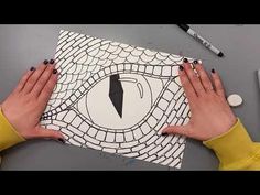 two hands on top of a piece of paper that has an eye drawn on it