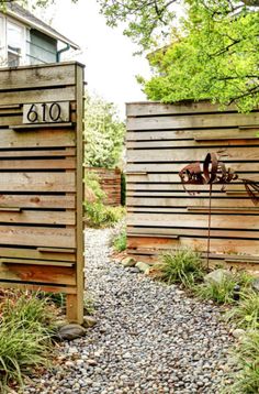 two wooden gates with numbers on them are in the middle of a gravel path surrounded by trees