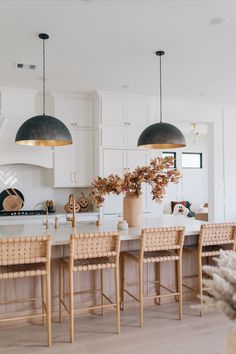 a large kitchen with white cabinets and wooden chairs in front of an island countertop