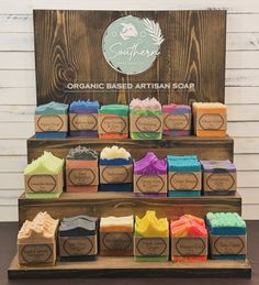 soaps are displayed on wooden shelves in front of a sign that reads organic based artisan soap