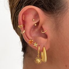 a woman wearing gold ear cuffs and piercings