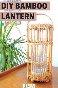 a bamboo lantern sitting on top of a wooden table next to a potted plant