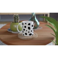 two coffee cups sitting on top of a wooden table next to a potted plant