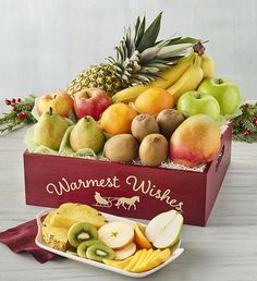 a wooden box filled with assorted fruit on top of a white table next to a red napkin