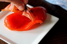 someone is cutting up an orange on a white square plate with a knife in it