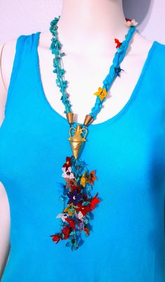 a woman wearing a blue top with flowers on it's neck and a gold pendant