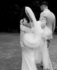 the bride and groom are walking together in black and white, holding each other's hands