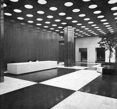 an empty room with black and white flooring, potted plants and lights on the ceiling