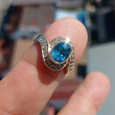 This stunning Sterling Silver Ring features a mirror polished finish and showcases a beautiful oval cut blue Zircon as the centerpiece, accented by 22 white CZ stones for added sparkle.  US Ring Size 5.5 The Ring is hallmarked 925 and measures 12 mm along the finger, making it a perfect statement piece for any occasion.  With a Zircon dimension of 8 mm x 6 mm, this Cocktail Ring is a unique and elegant gift for her that is sure to impress. Blue Zircon Ring, Natural Gemstone Ring, 925 Ring, Zircon Ring, Ring Oval, Blue Zircon, Blue Band, Jewelry Maker, Cz Stone