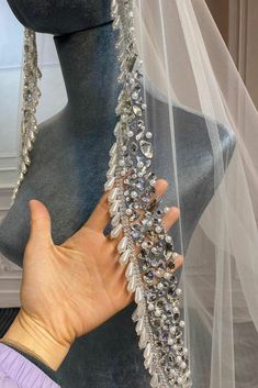 a woman is holding up a veil with crystals on it