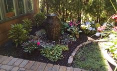 a garden with flowers and rocks in front of a house