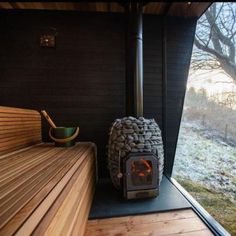 a wood burning stove sitting inside of a wooden cabin next to a window with a view