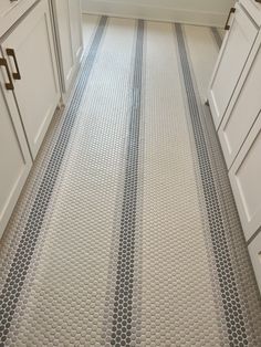 a kitchen with white cabinets and gray patterned flooring on the walls, along with an area rug that looks like hexagonal tiles