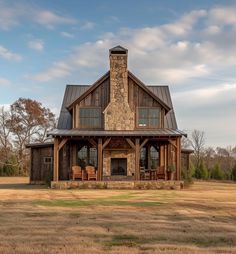 a large house with a stone chimney in the middle of a field