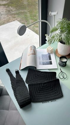 two black knitted gloves sitting on top of a table next to an open book