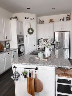 a kitchen with white cabinets and wooden cutting boards hanging on the wall next to an island