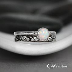 a white opal ring sitting on top of a black and white cloth covered surface