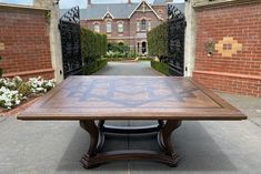 a large wooden table sitting in front of a brick building with an archway leading to it