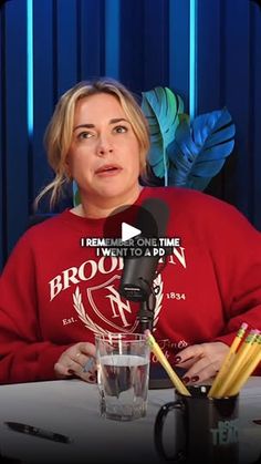 a woman sitting at a table in front of a microphone with pencils next to her