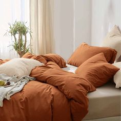 an unmade bed with orange sheets and pillows