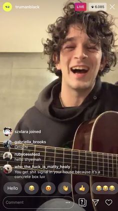 a man with curly hair is playing an acoustic guitar and singing into the phone screen