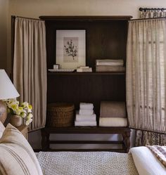 a bed room with a neatly made bed and a shelf full of towels on top of it