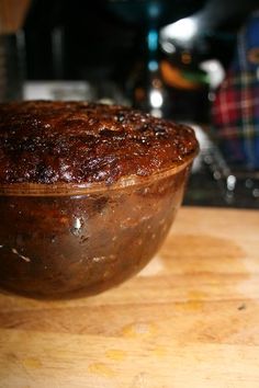 a wooden bowl sitting on top of a table next to a knife and some food