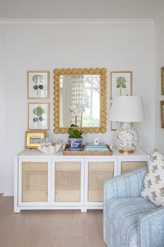 a living room filled with furniture and framed pictures on the wall above a white table