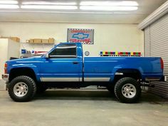 a blue pick up truck parked in a garage next to a storage area with roller doors