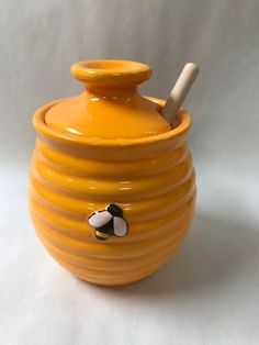 a yellow honey jar with a wooden stick sticking out of it's top, on a white background