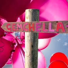 a wooden sign that says genchelia on it next to balloons and a pole