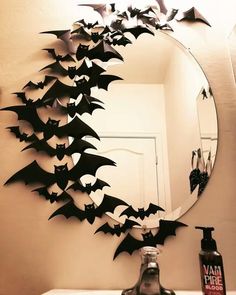 a mirror that has bats on it in the shape of a wreath above a sink