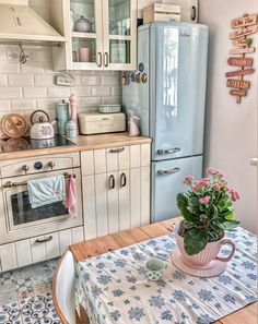 a kitchen with an old fashioned refrigerator, table and flowers on the dining room table