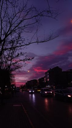 cars are parked on the side of the road at night with pink and purple clouds