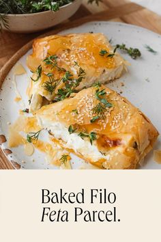 baked filo feta parcel on a white plate with herbs in a bowl behind it