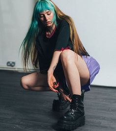 a woman with green hair is sitting on the floor