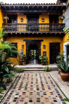 a yellow building with lots of plants and potted plants on the front porchs