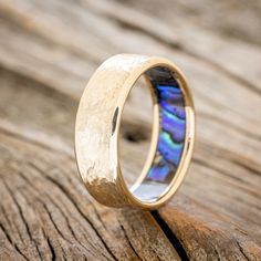 a wedding ring with an abangani shell inlay on top of it, sitting on a piece of wood