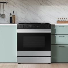 an oven in a kitchen with green cabinets and marble counter tops on the wall behind it