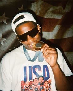 a man wearing sunglasses and eating a donut with an american flag in the background