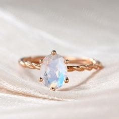 a ring with an oval white stone in the center on top of a white cloth